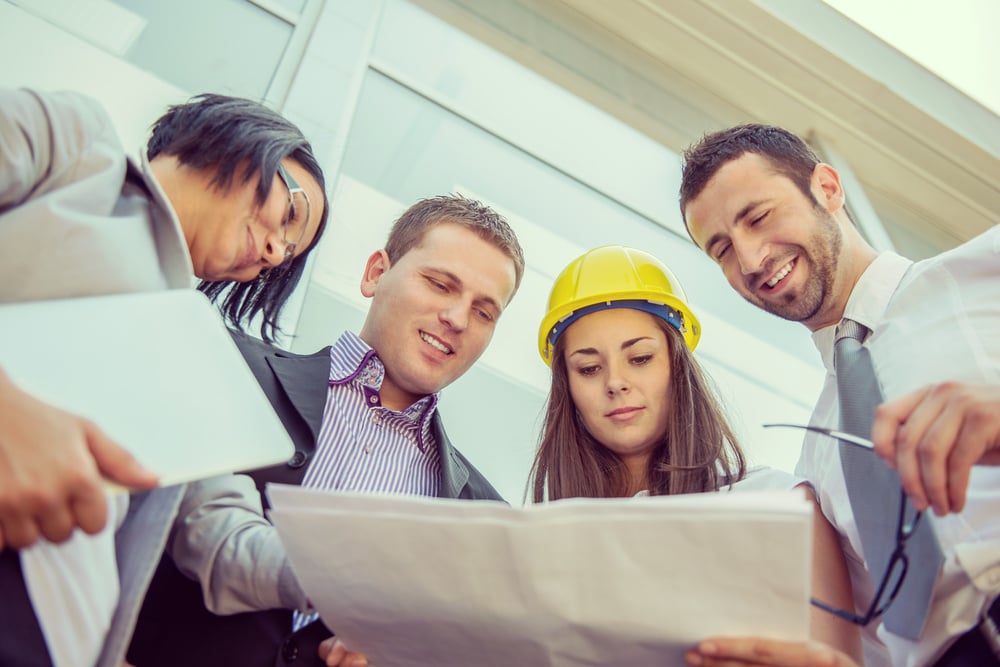 Colleagues reading construction documents in front of building